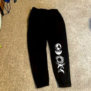 These are black sweat pants that have a moon and sun on the side.
